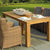 Wooden outdoor dining table with wicker chairs on a stone patio